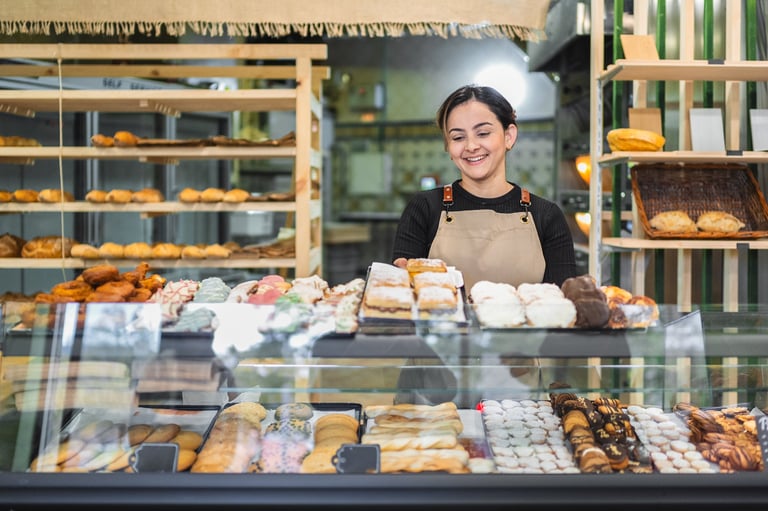 Female baker arranging fresh pastries in a display case